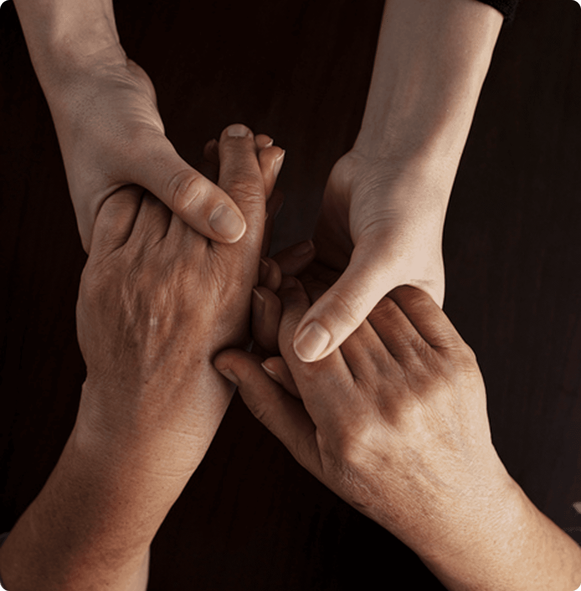 Two pairs of hands clasping together